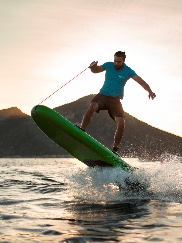 Wynajem desek jet surfingowych. Deska surfingowa na tle zachodzącego słońca