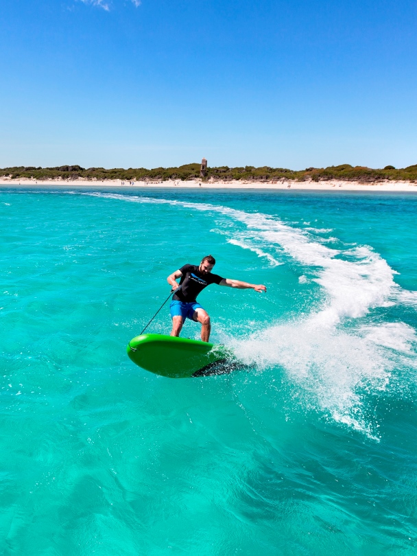 Wynajem desek jet surfingowych. Surfer wykonujący trik na desce