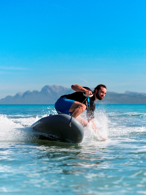 Wynajem desek jet surfingowych. Surfer wykonujący trik na desce