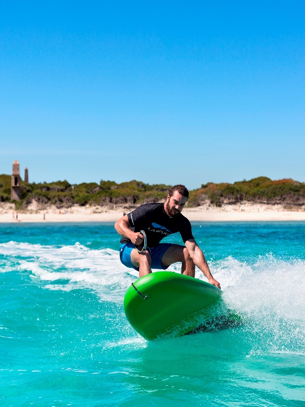 Wynajem desek jet surfingowych. Surfer wykonujący trik na desce