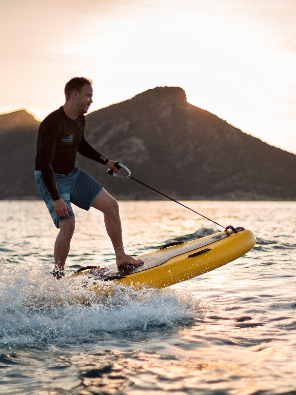 Wynajem desek jet surfingowych. Deska surfingowa na tle zachodzącego słońca